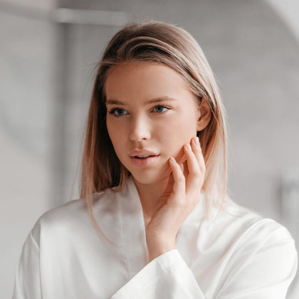 Girl in white robe in bathroom touching face Girl in white robe in bathroom touching face