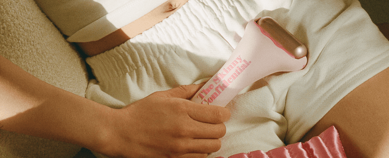 woman using pink facial roller 