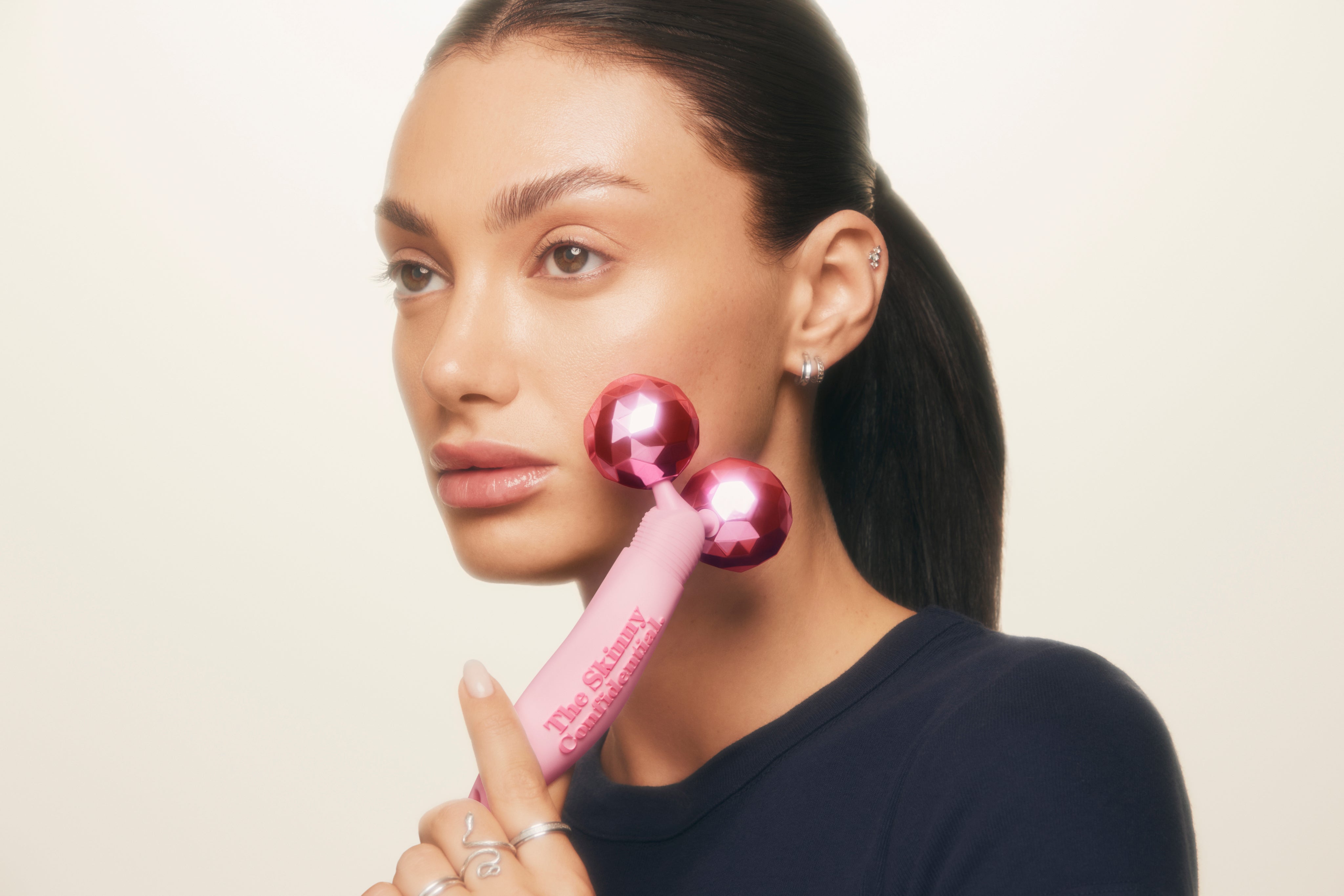 woman using pink facial roller beauty tool
