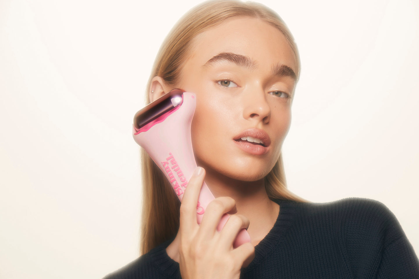 woman using pink facial roller beauty tool